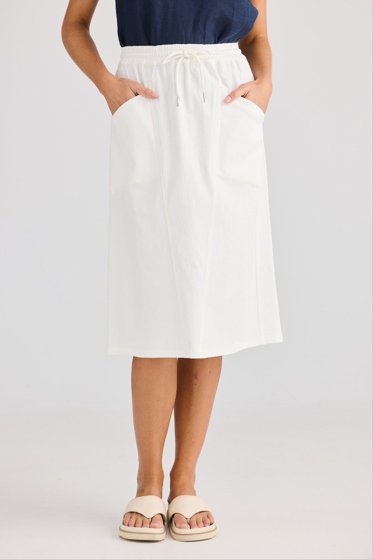 Person wearing a white skirt and navy top on a light gray background