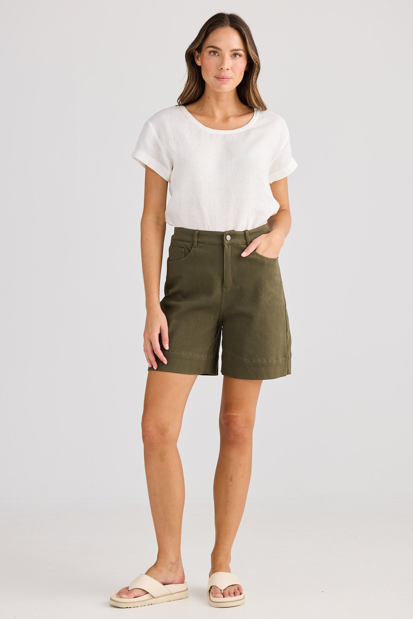 Woman wearing a white top and green shorts on a plain background