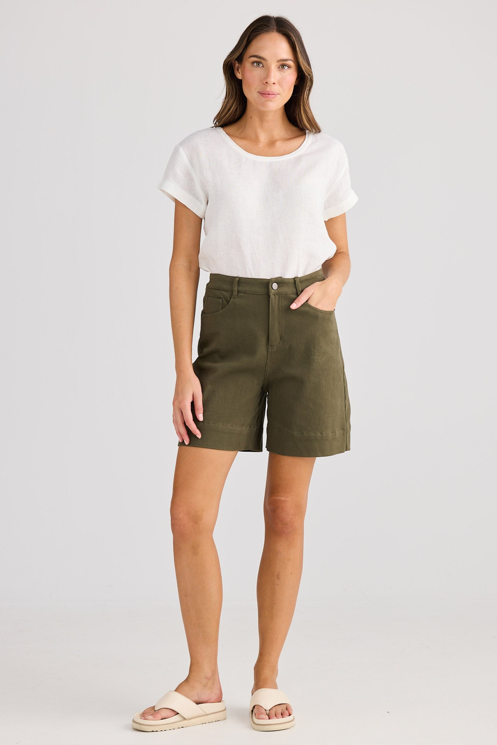 Woman wearing a white top and green shorts on a plain background