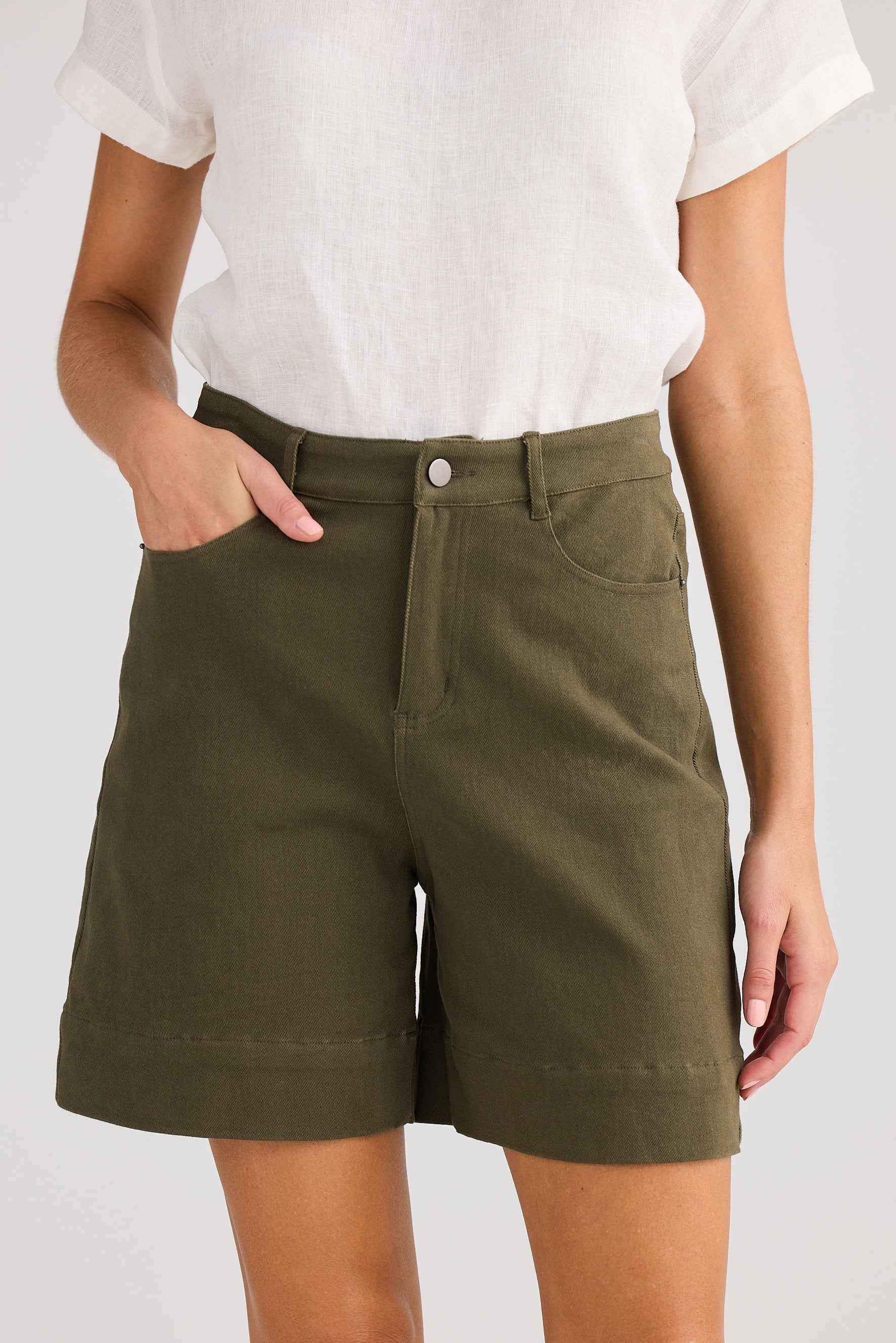 Person wearing olive green shorts on a plain background