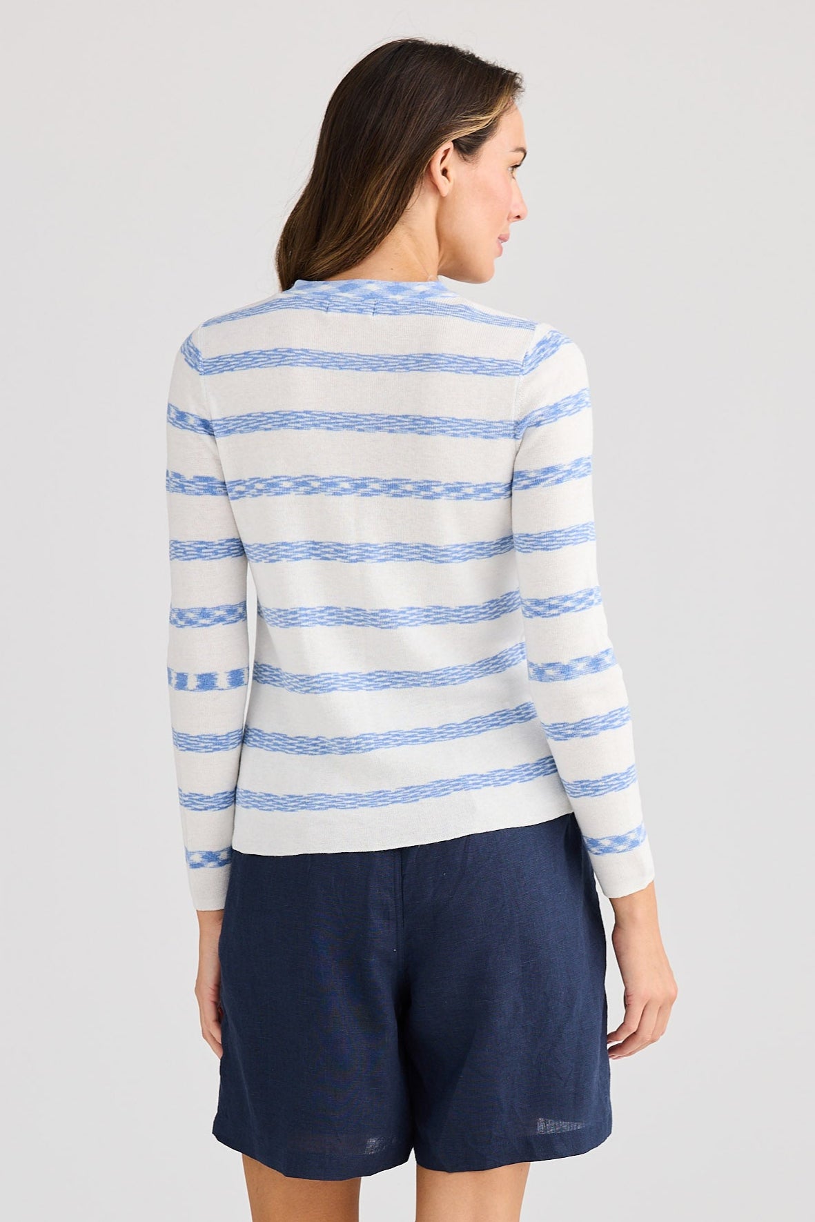 Woman wearing a striped sweater and navy shorts on a light gray background