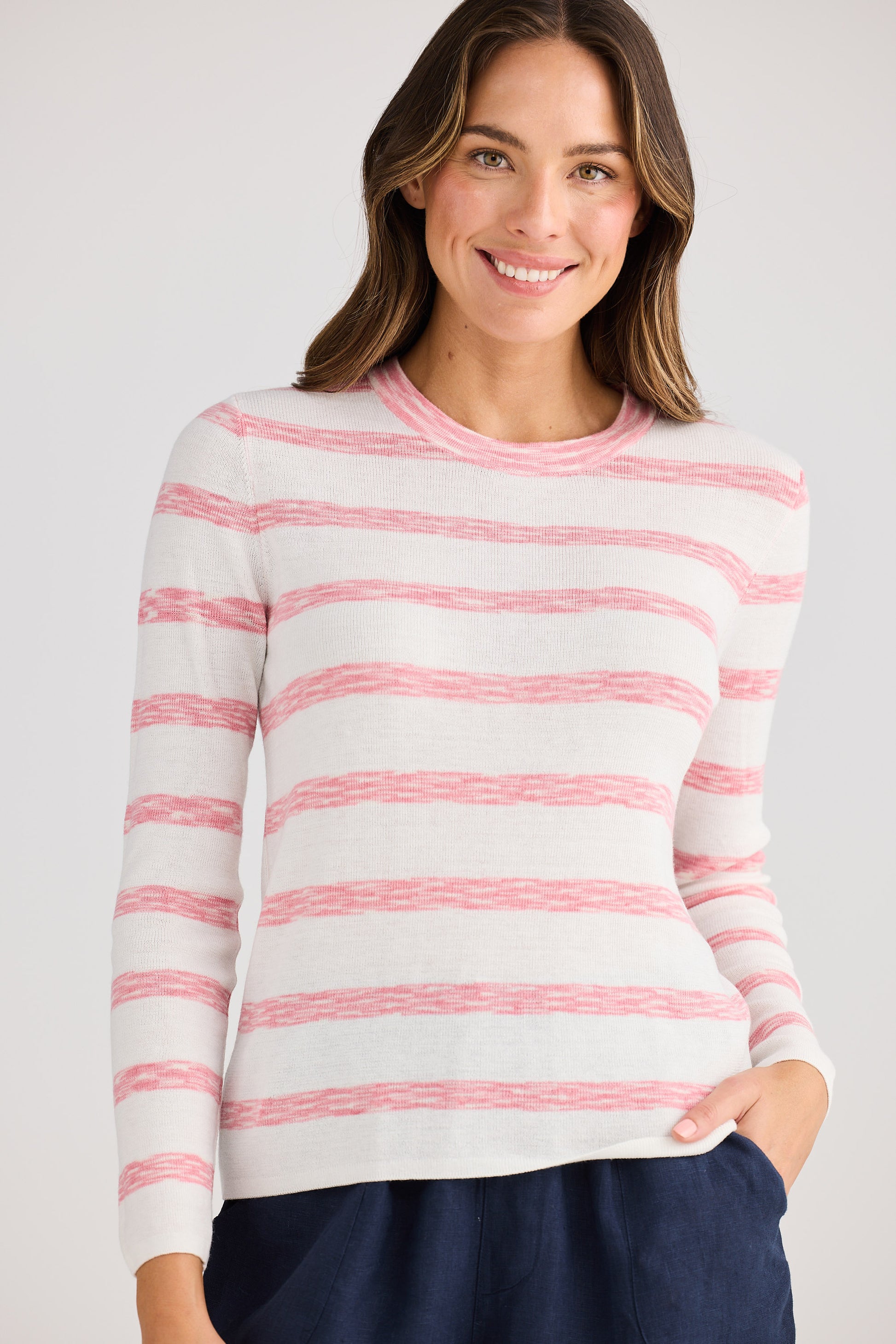 Woman wearing a white sweater with pink stripes against a plain background