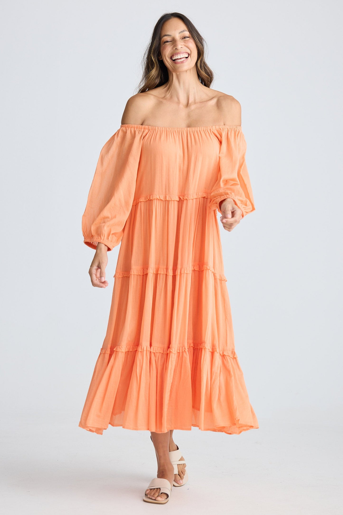 Woman wearing an orange off-shoulder dress on a white background