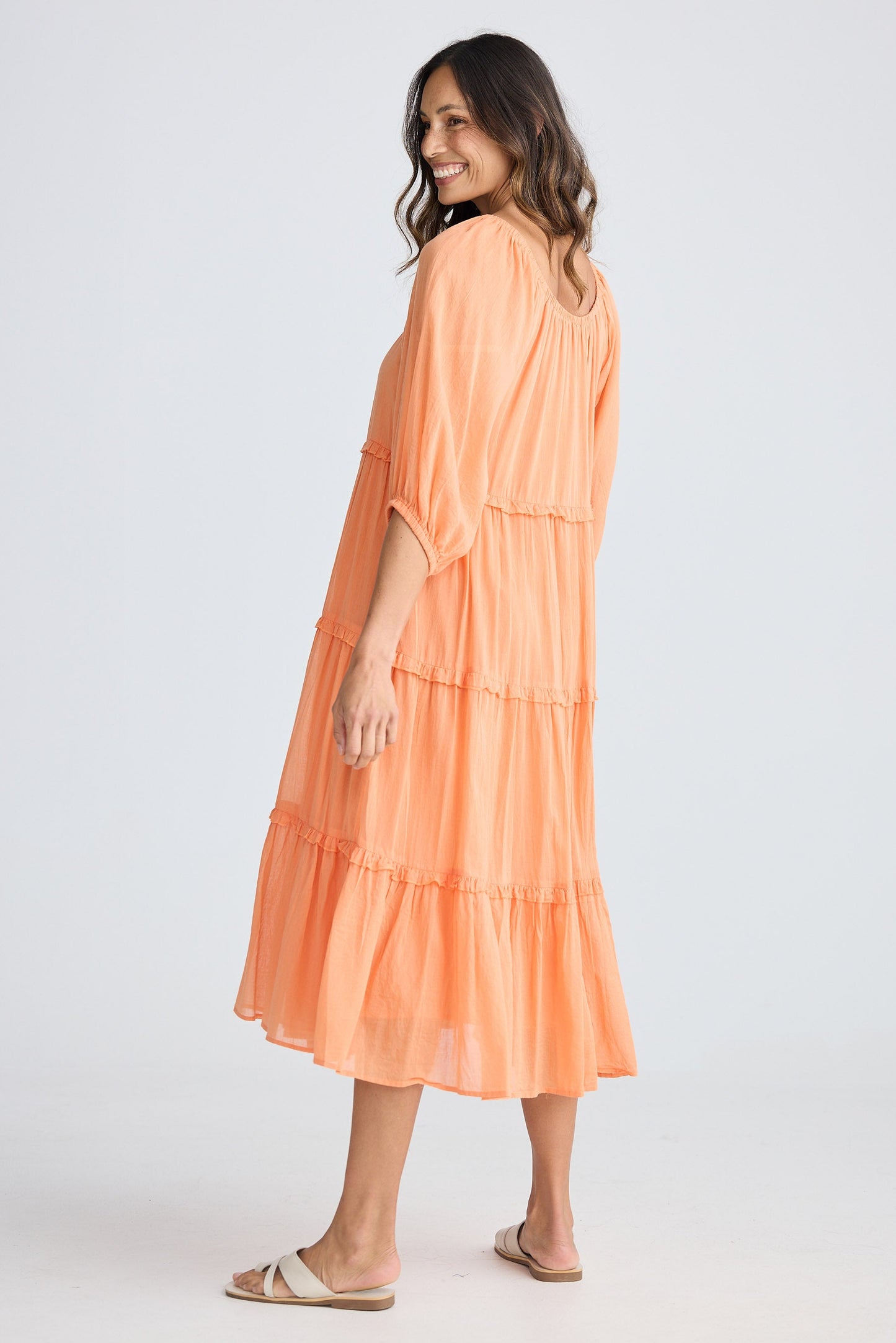 Woman wearing a peach-colored dress on a white background