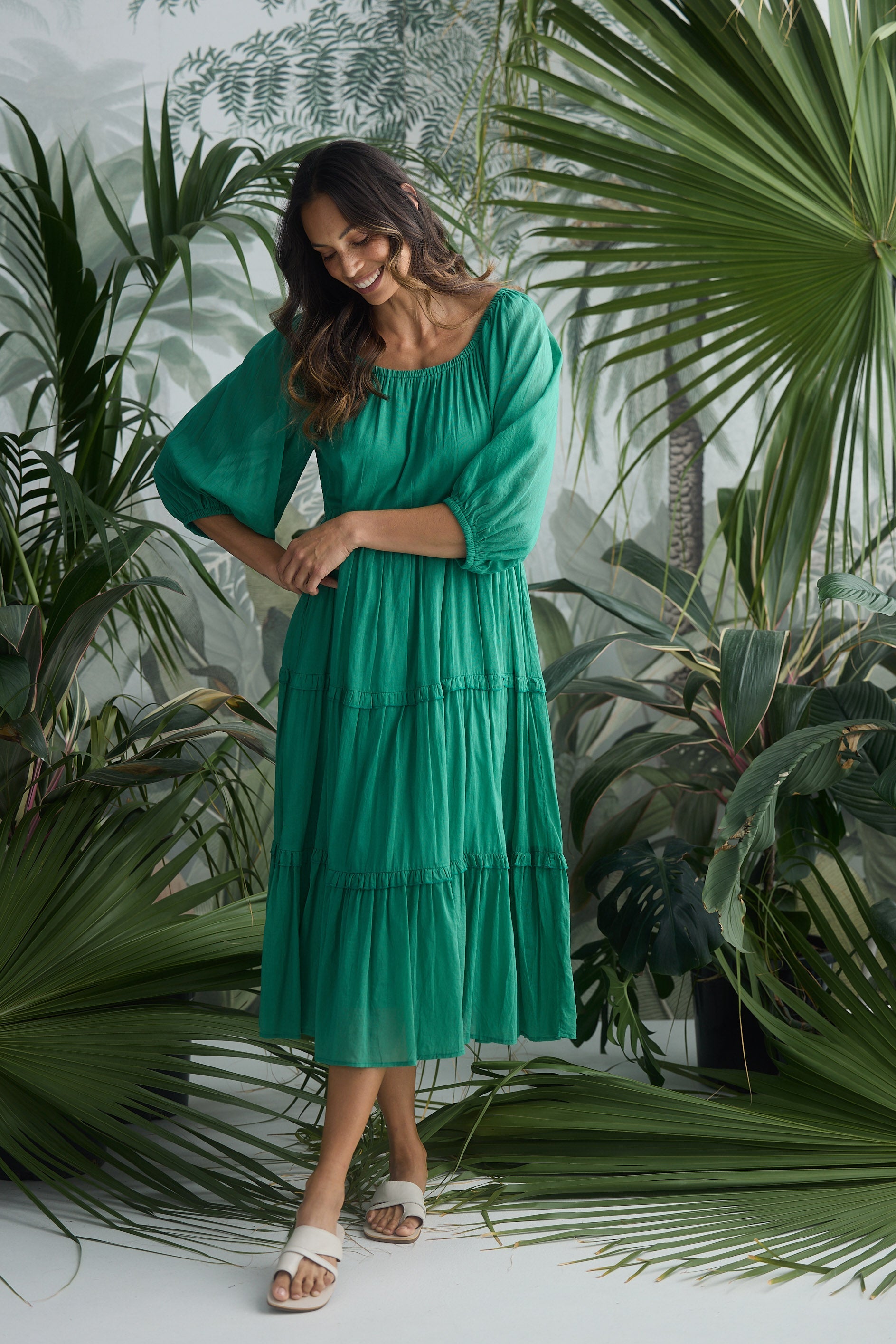Woman in a green dress standing among tropical plants