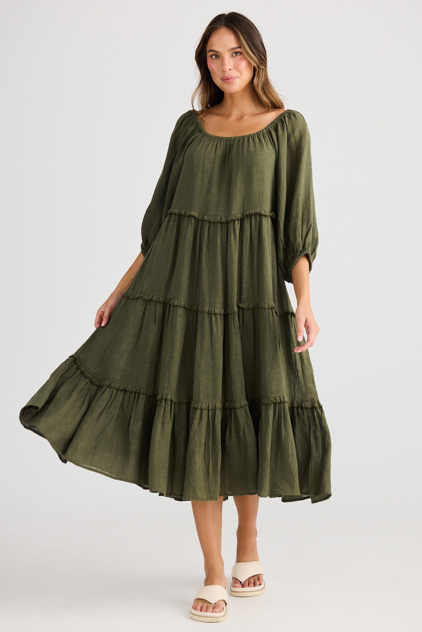 Woman wearing a green tiered dress on a white background