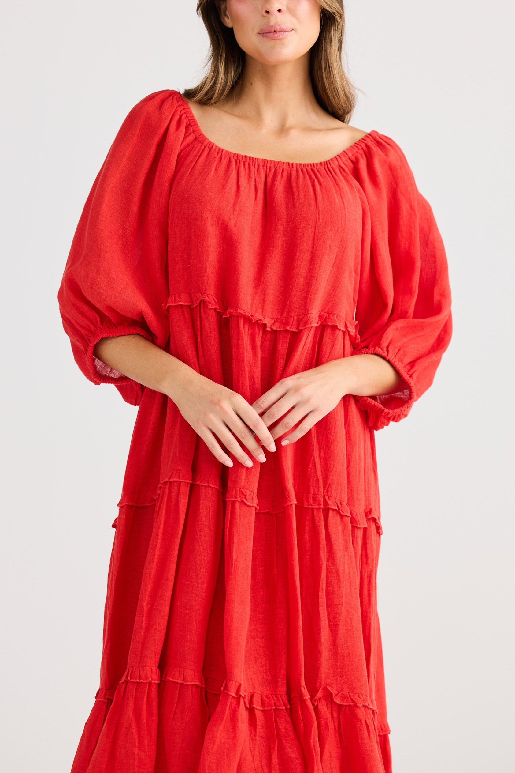 Woman wearing a red dress with tiered layers on a white background