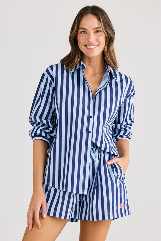 Woman wearing a blue and white striped shirt dress on a plain background