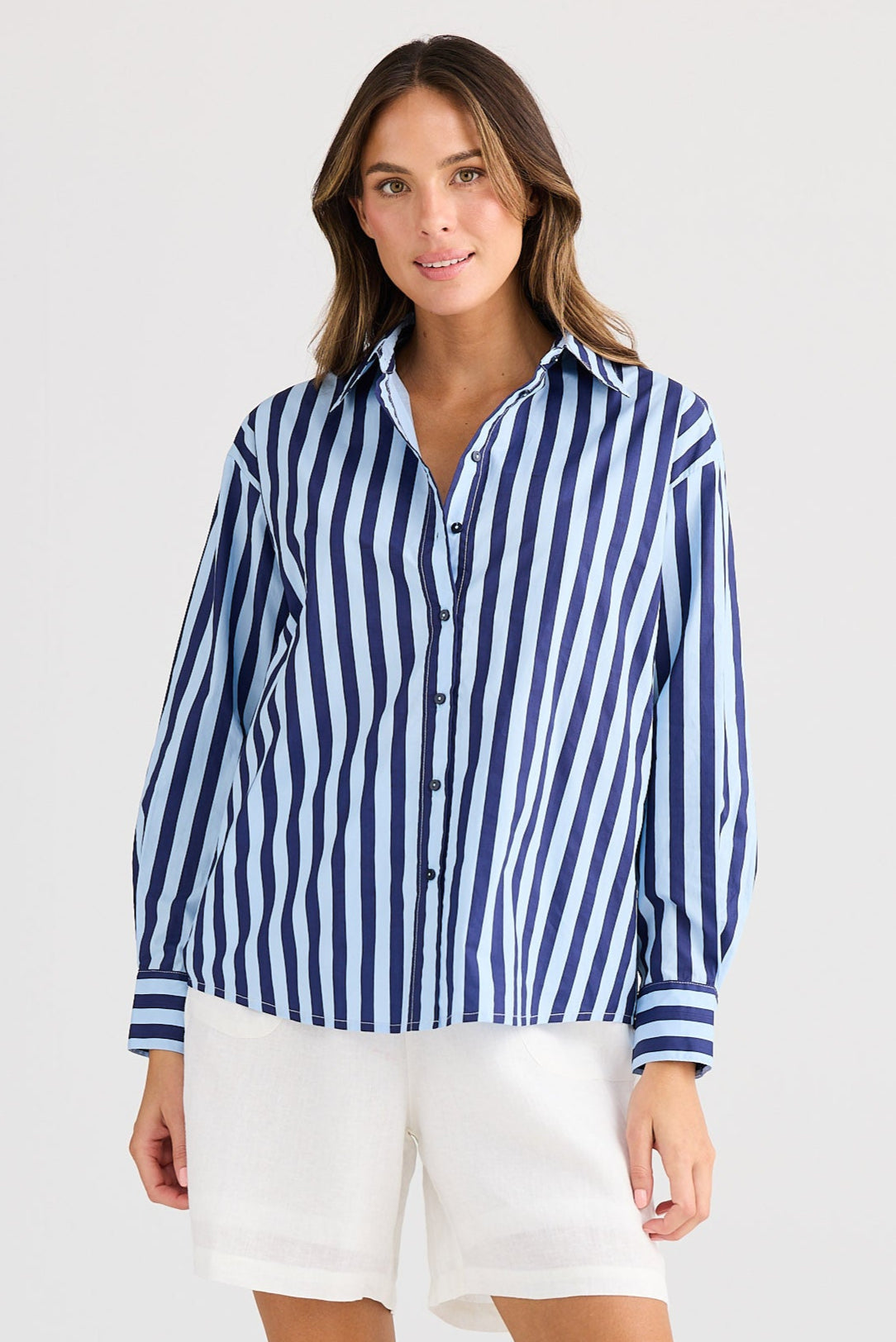 Woman wearing a blue and white striped shirt and white shorts on a white background