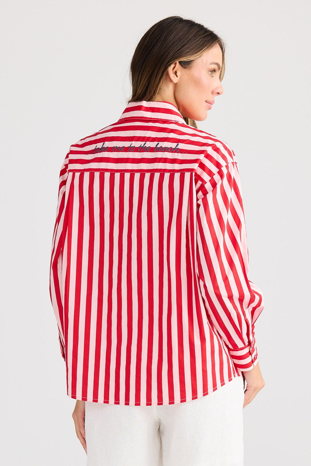 Woman wearing a red and white striped shirt and white shorts on a plain background