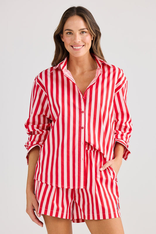 Woman wearing a red and white striped pajama set on a plain background
