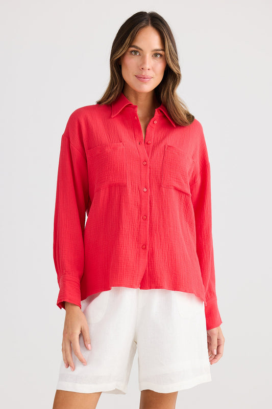 Woman wearing a red shirt and white shorts on a plain background