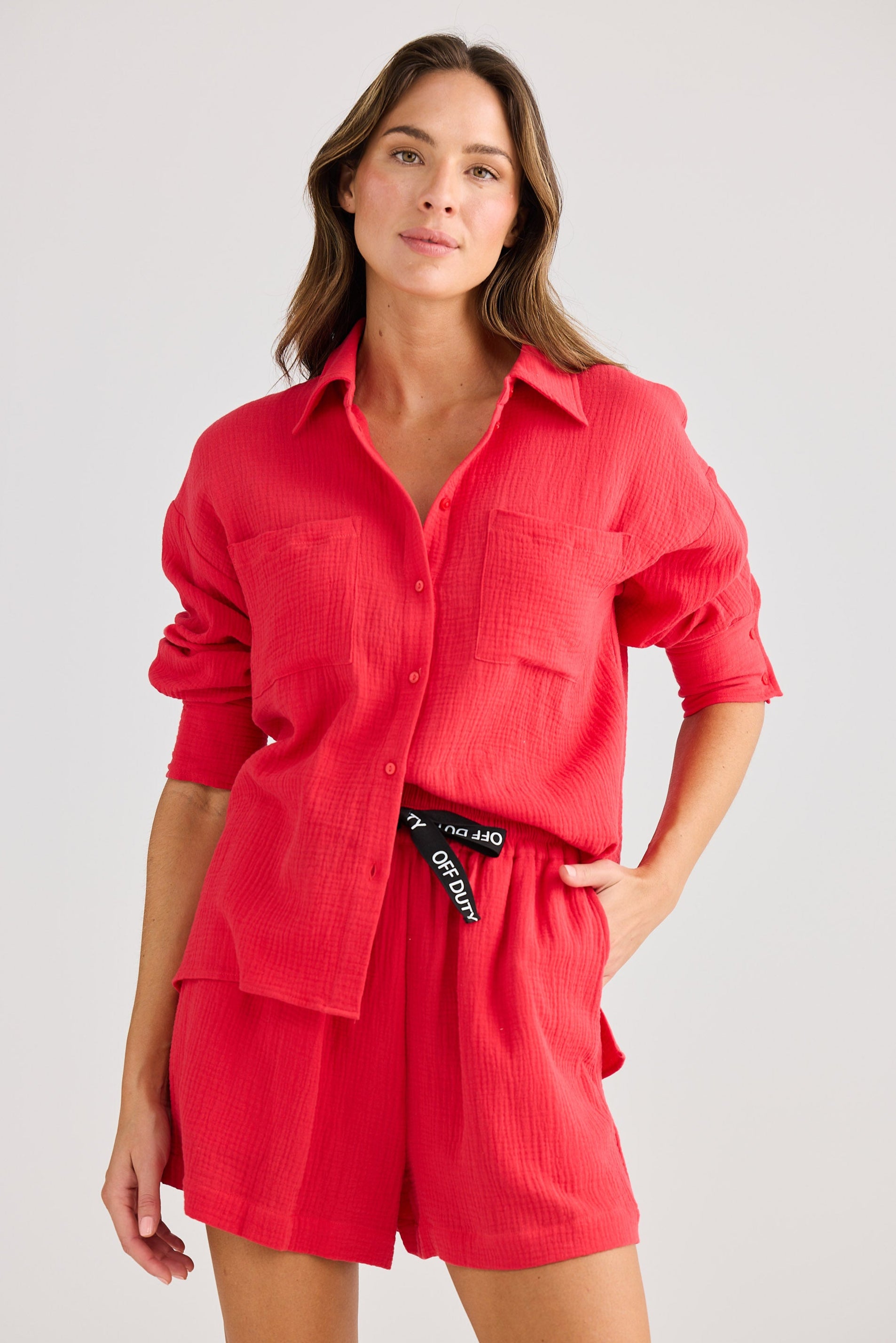 Woman wearing a red outfit with a visible brand label on a plain background