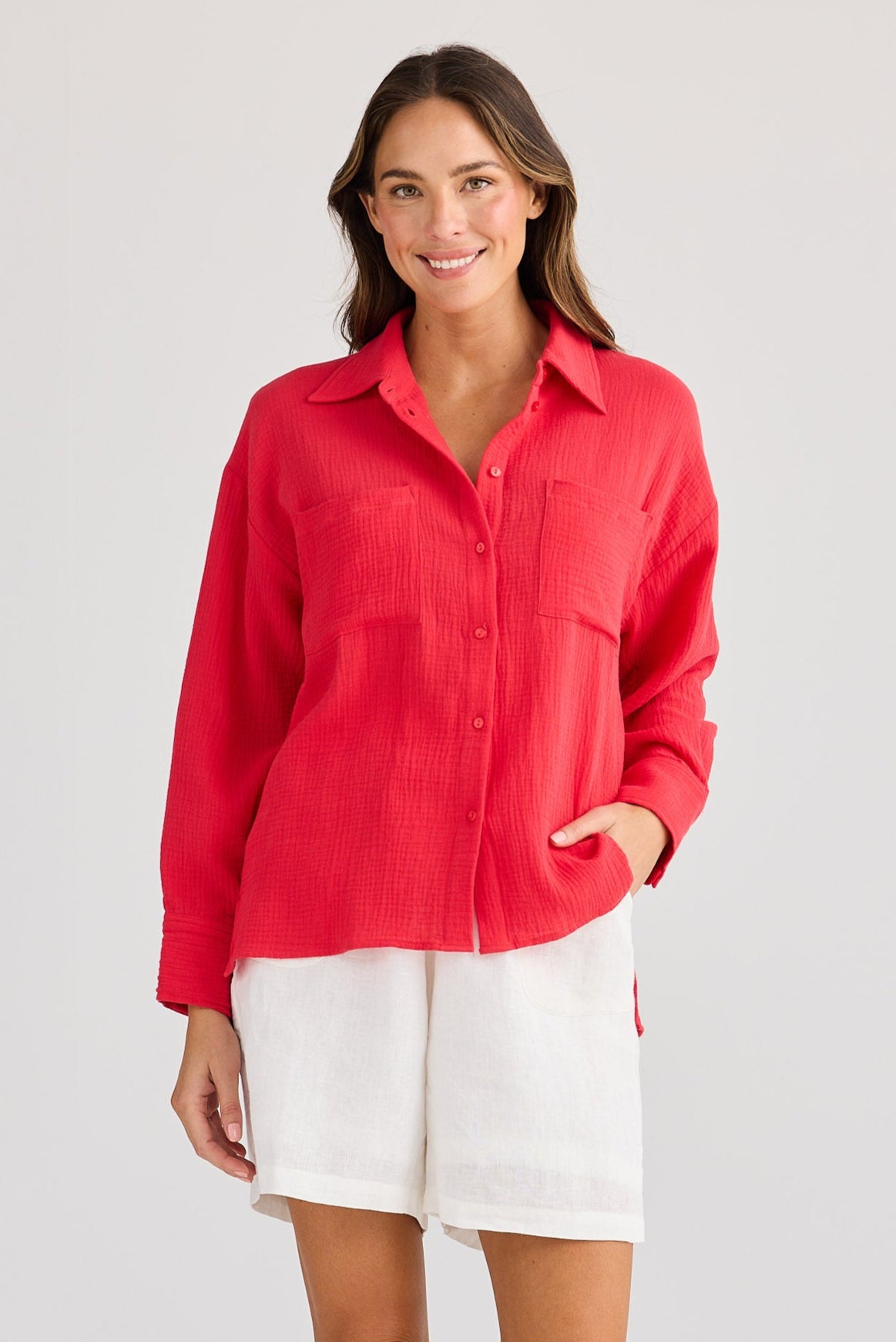 Woman wearing a red shirt and white shorts on a light gray background