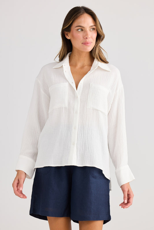 Woman wearing a white shirt and navy shorts on a plain background