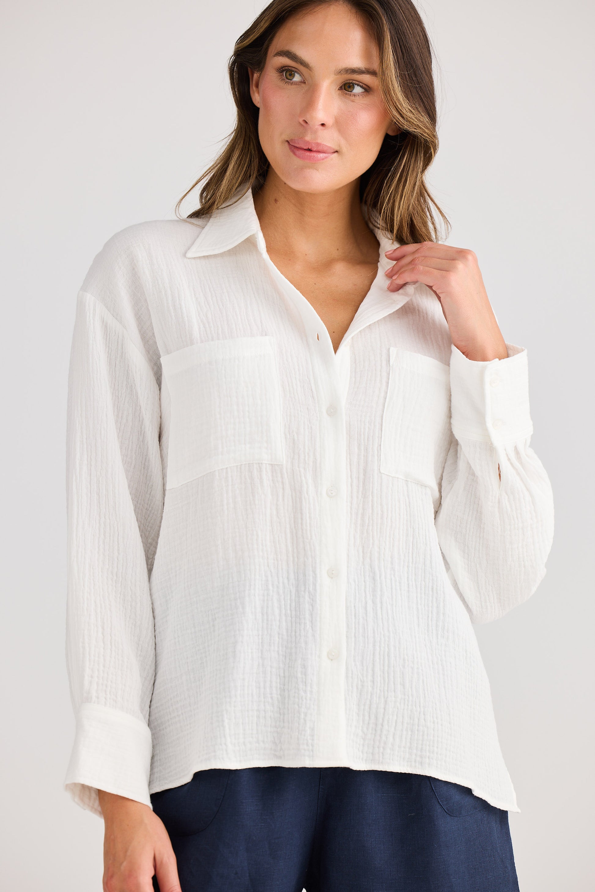 Woman wearing a white button-up shirt against a plain background