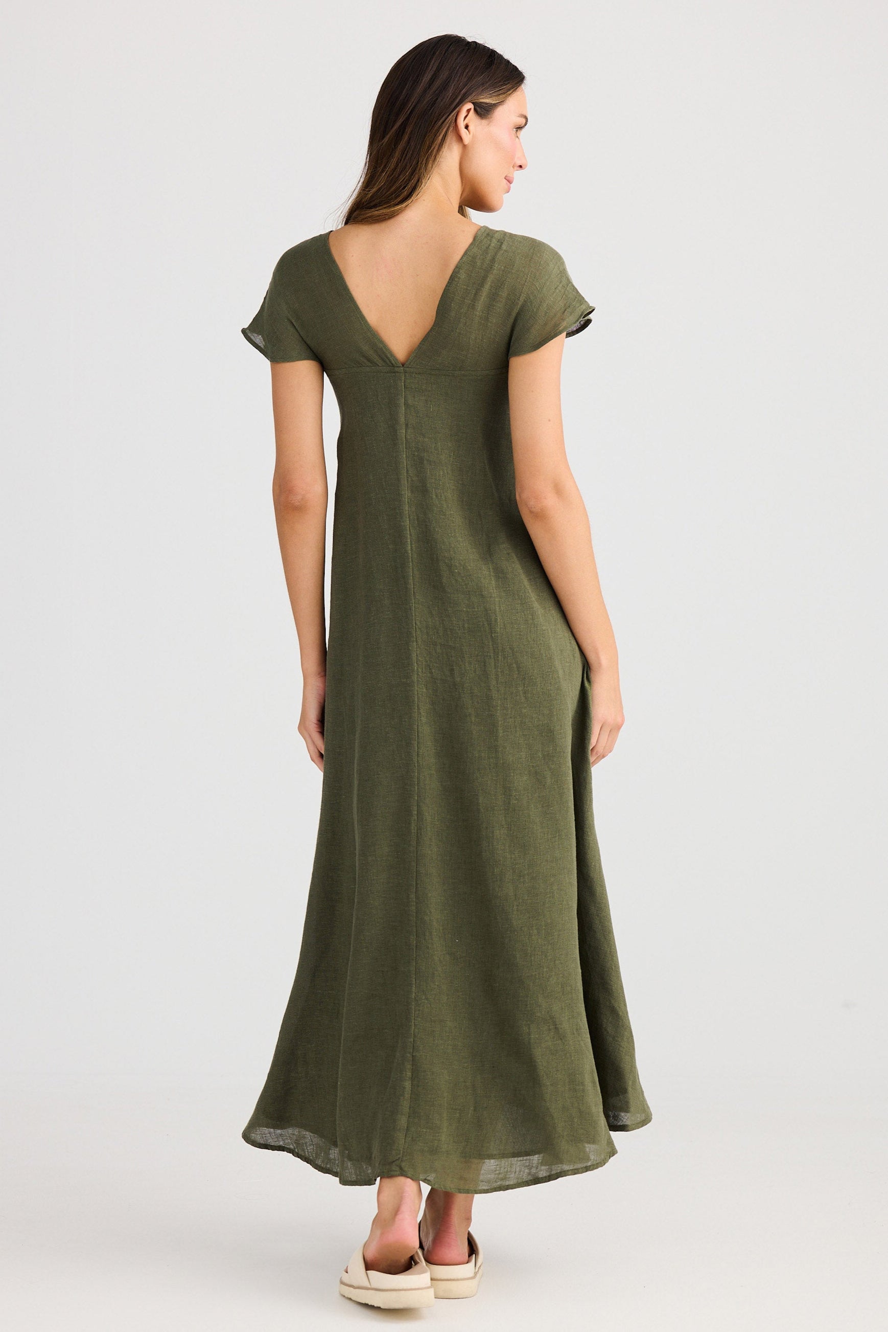 Woman wearing a green dress with a V-neck and cap sleeves on a white background