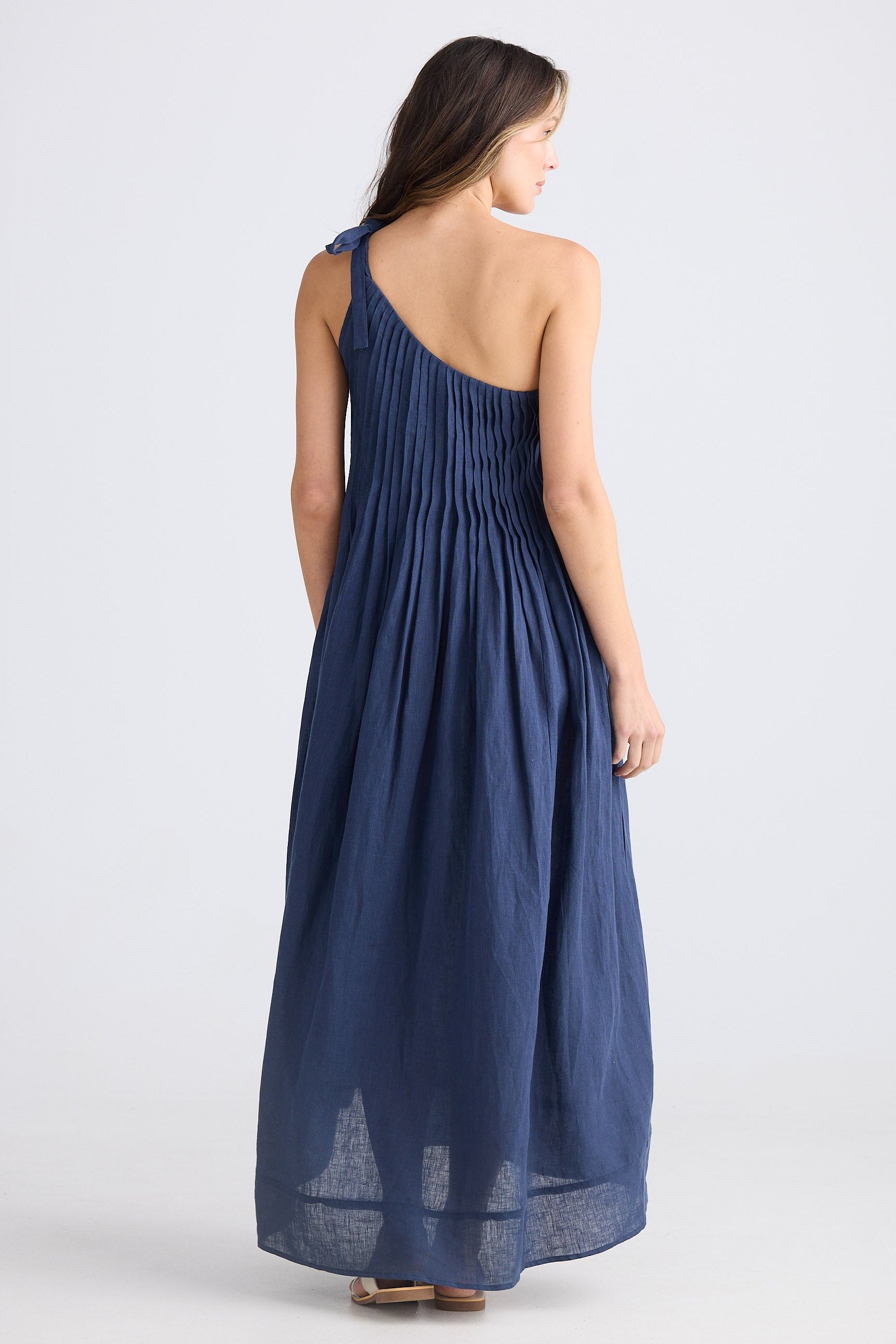Female wearing one shoulder maxi dress in navy on white background
