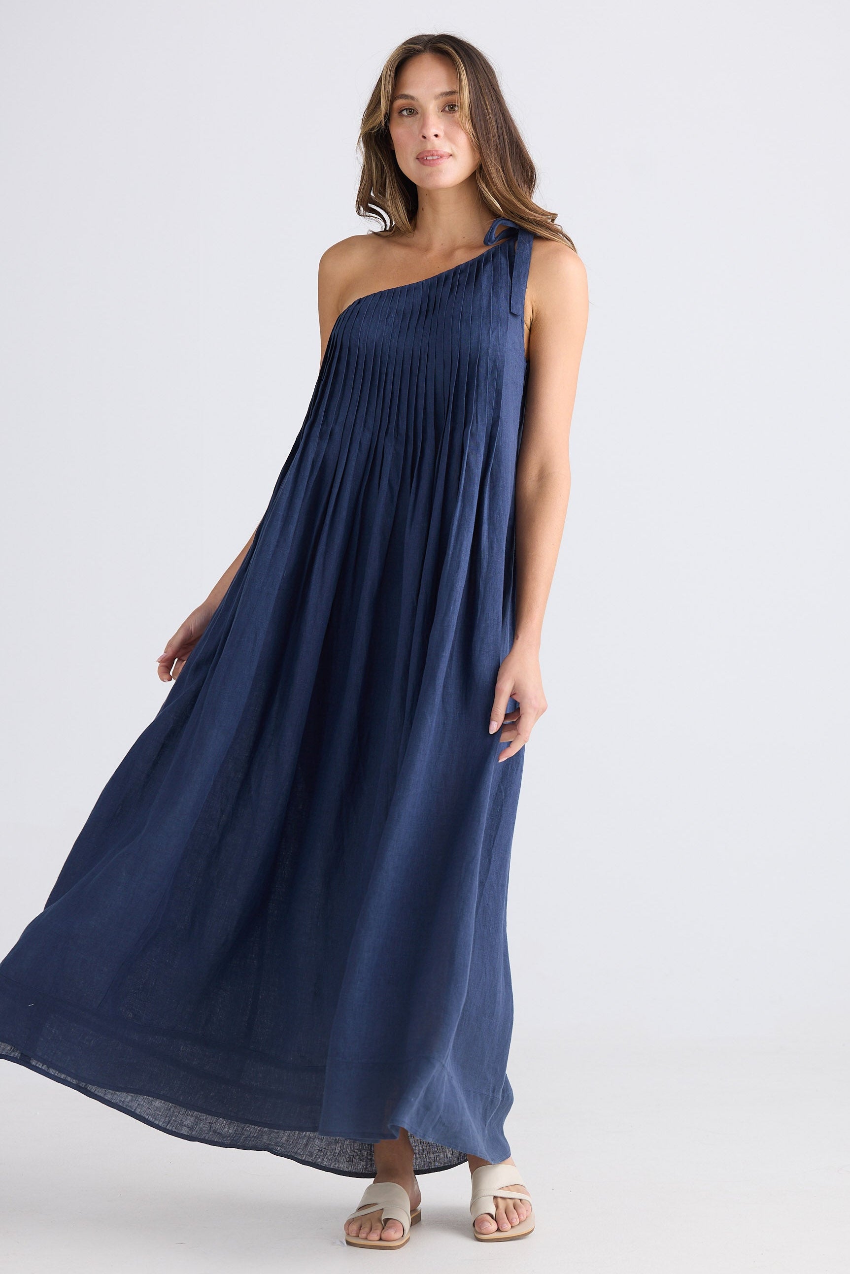 Female wearing one shoulder maxi dress in navy on white background