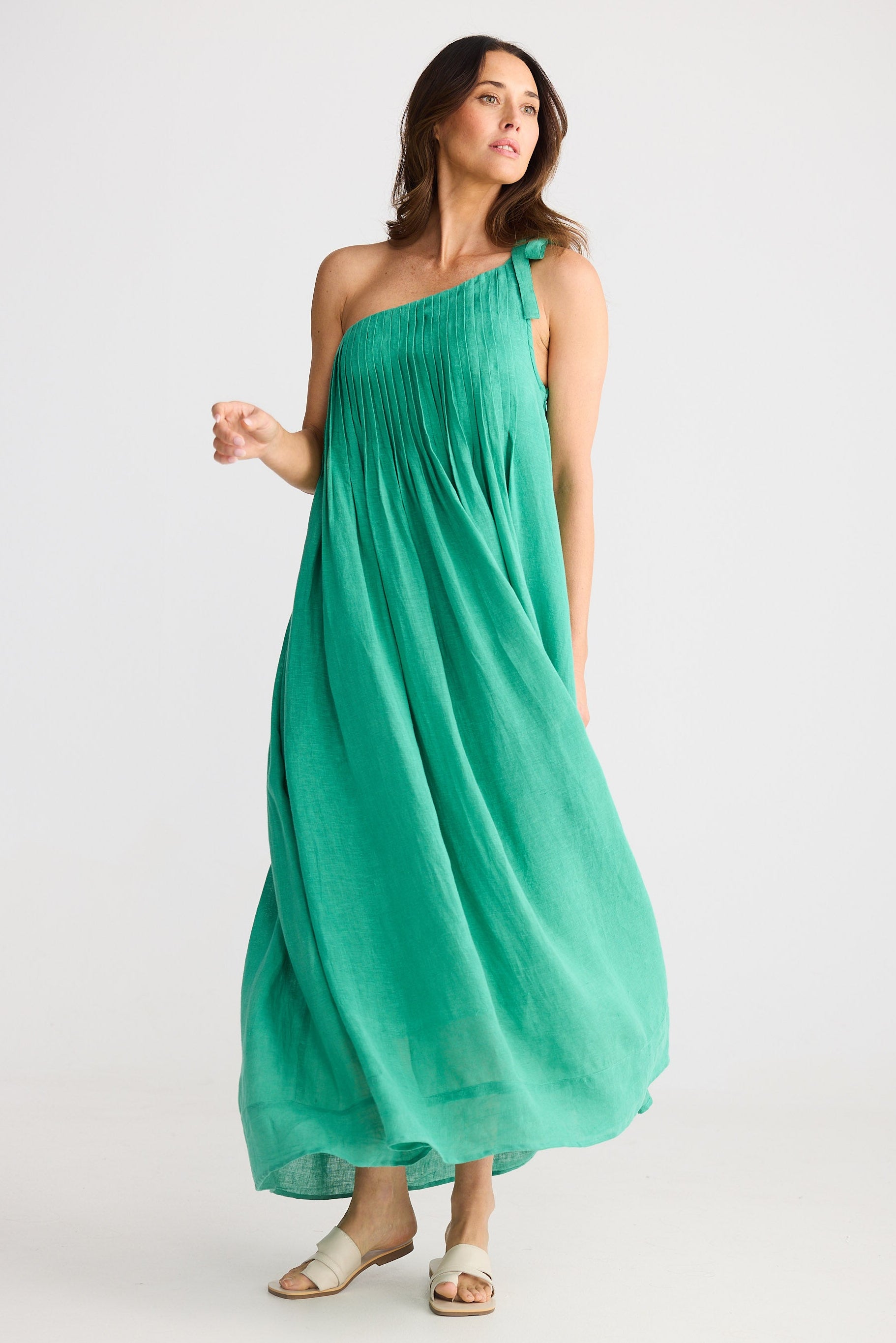 Woman wearing one shoulder green maxi dress on white background