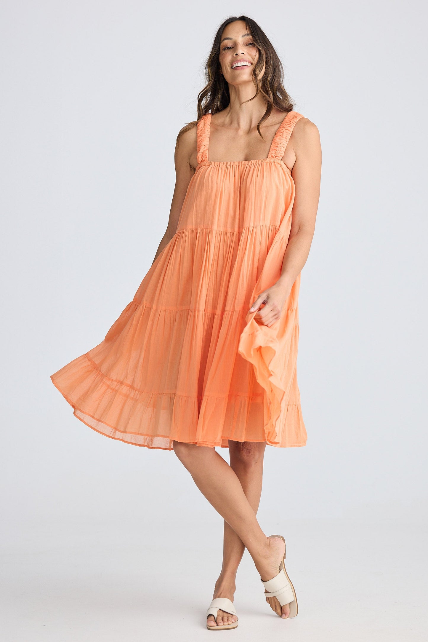 Woman wearing a peach-colored dress against a white background