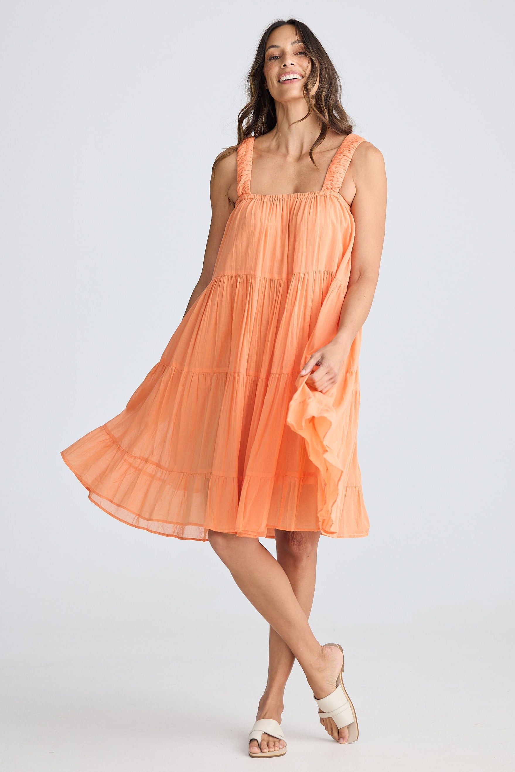 Woman wearing a peach-colored dress against a white background