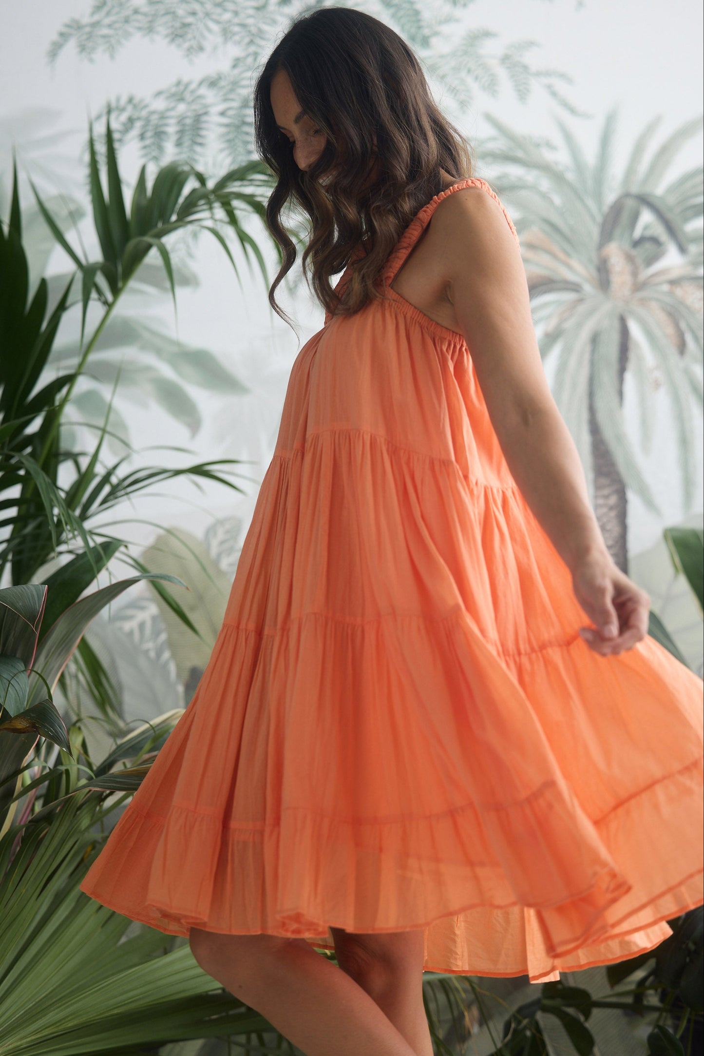 Woman in an orange dress standing among green plants