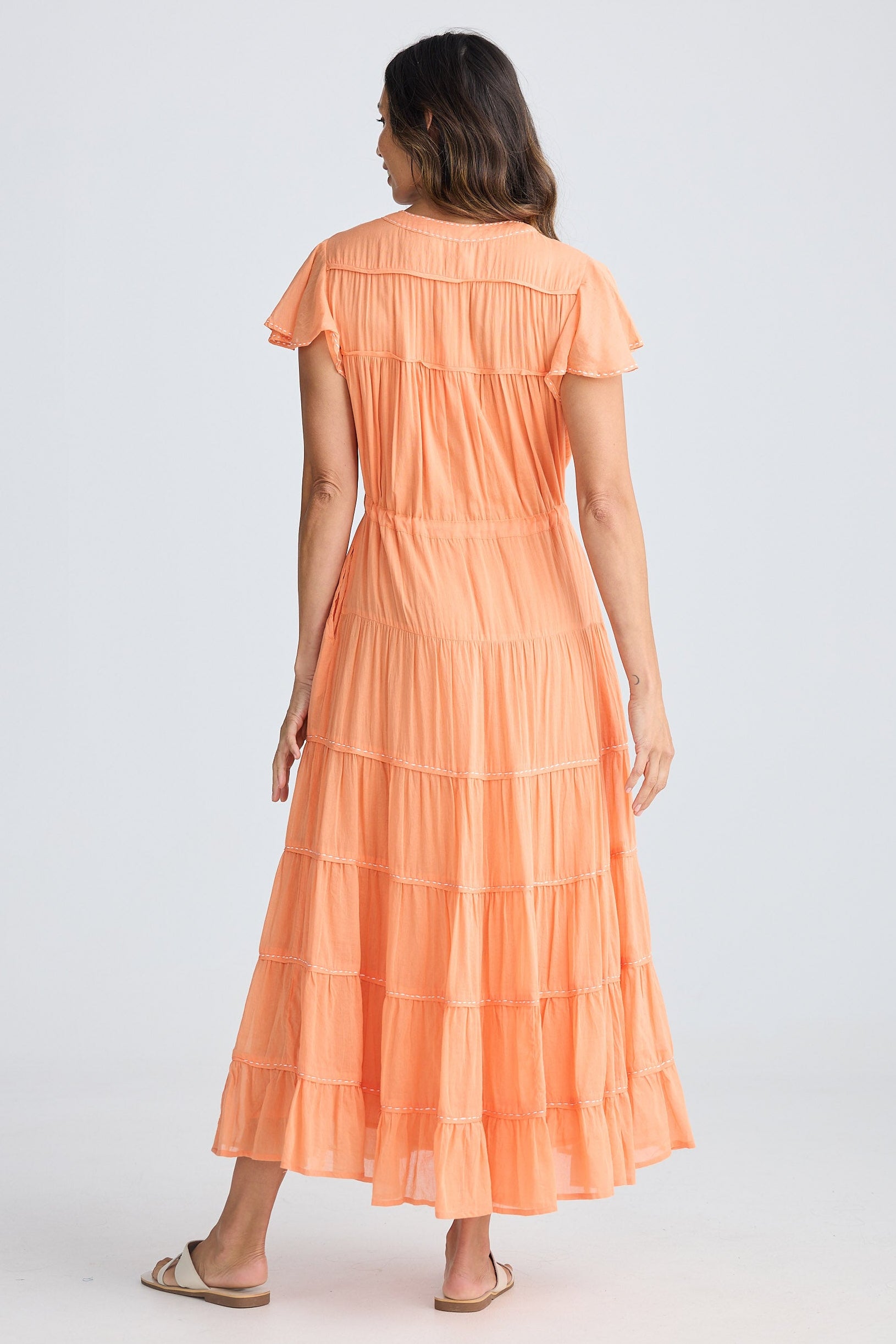 Woman wearing a peach-colored dress on a white background