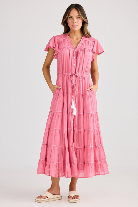 Woman wearing a pink dress with ruffled sleeves on a white background