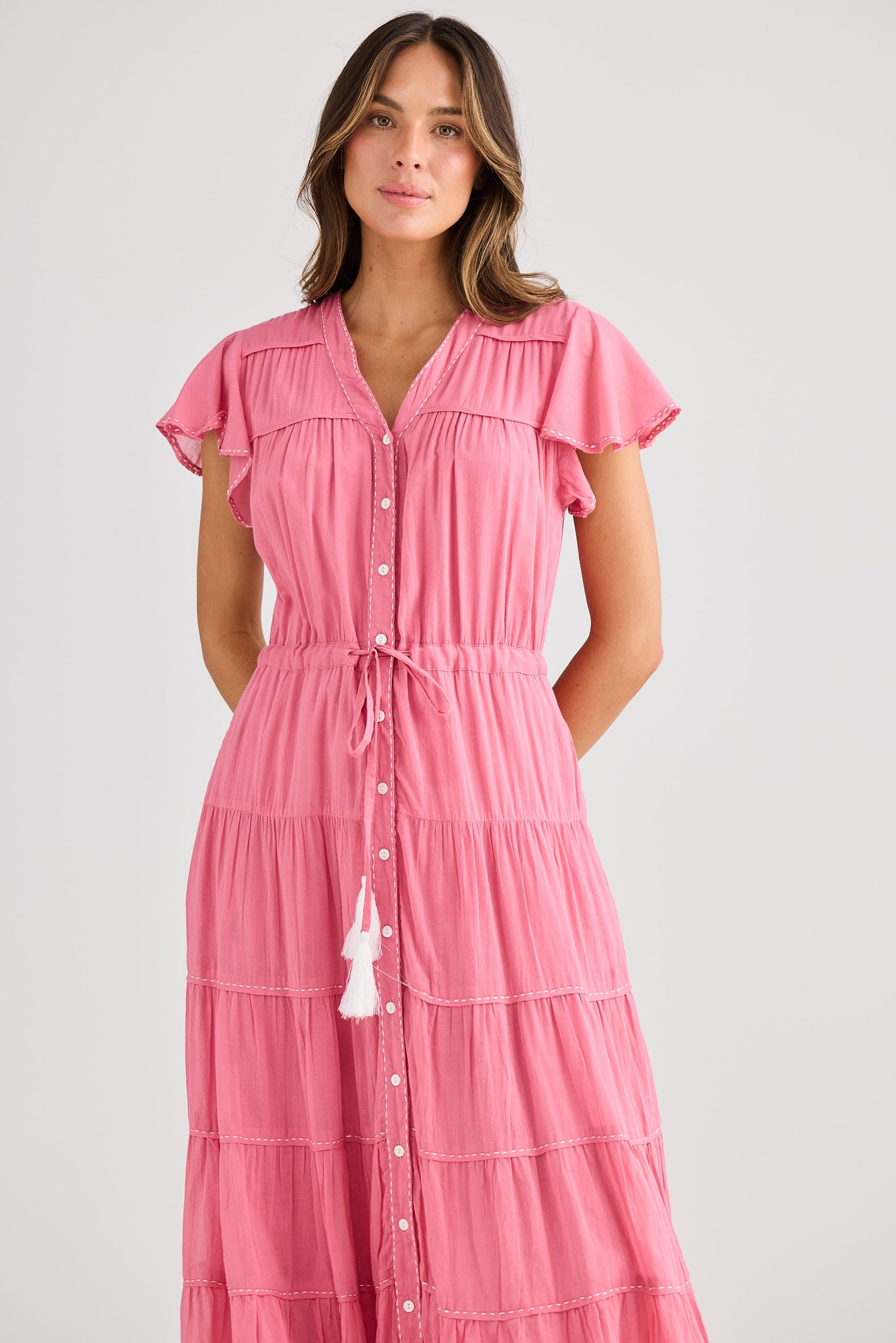 Woman wearing a pink dress with ruffled sleeves on a white background
