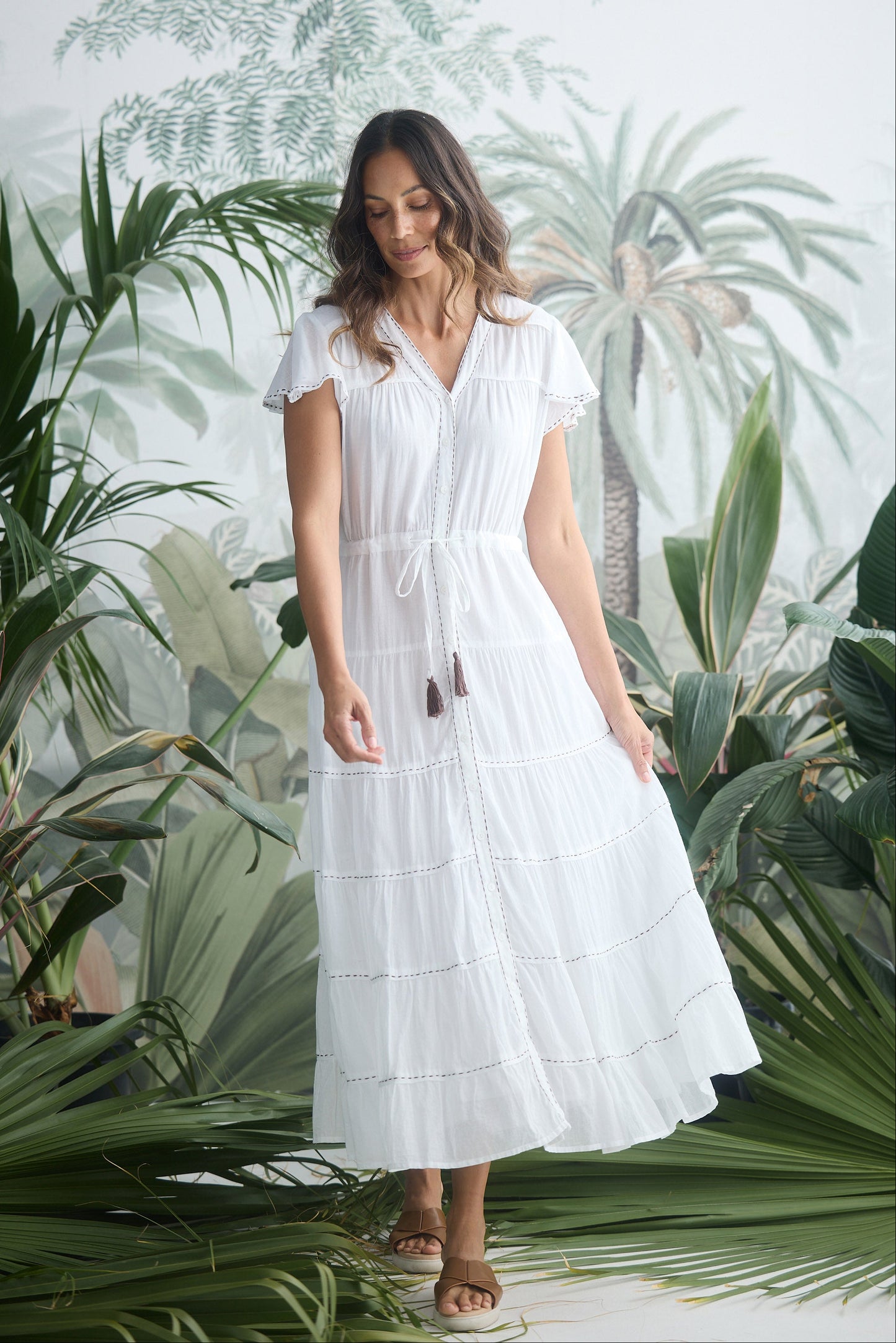 Woman in a white dress standing among tropical plants