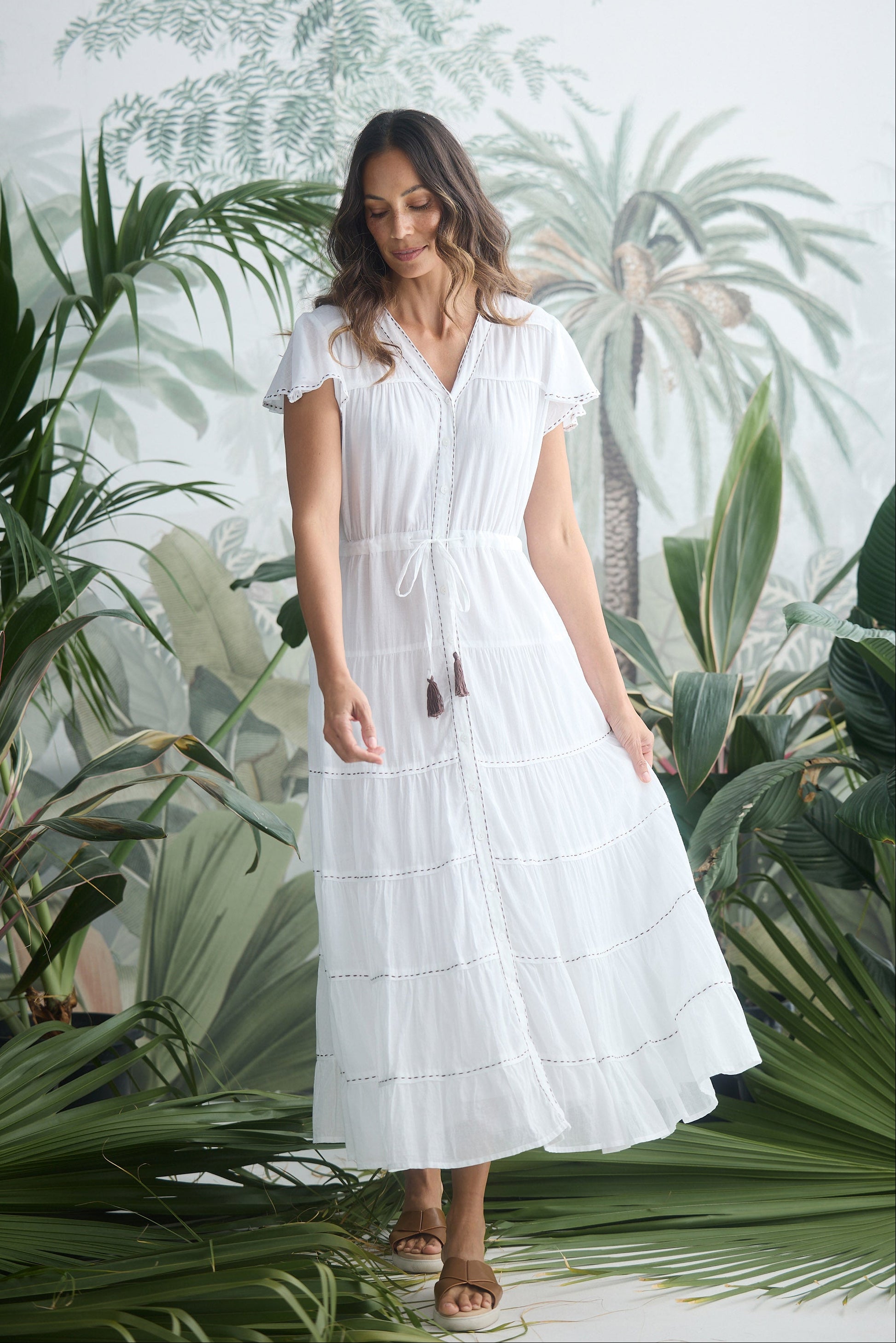 Woman in a white dress standing among tropical plants