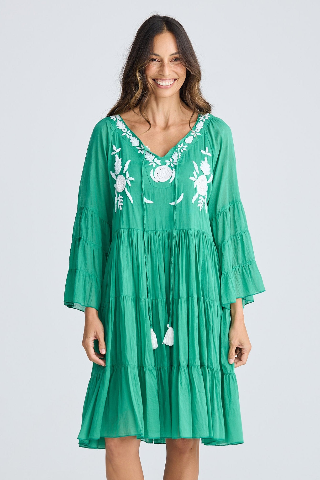 Woman wearing a green dress with white embroidery on a white background