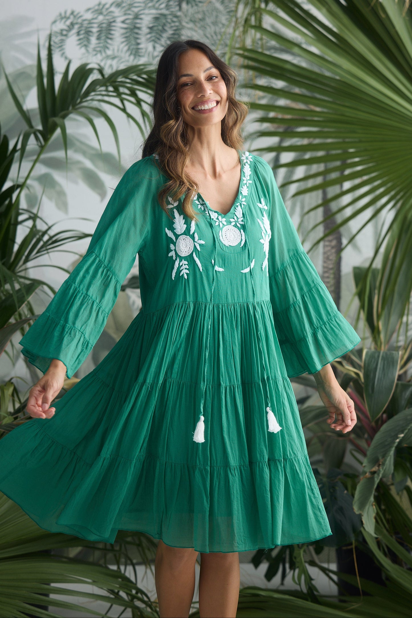 Woman wearing a green dress with white embroidery in a tropical setting