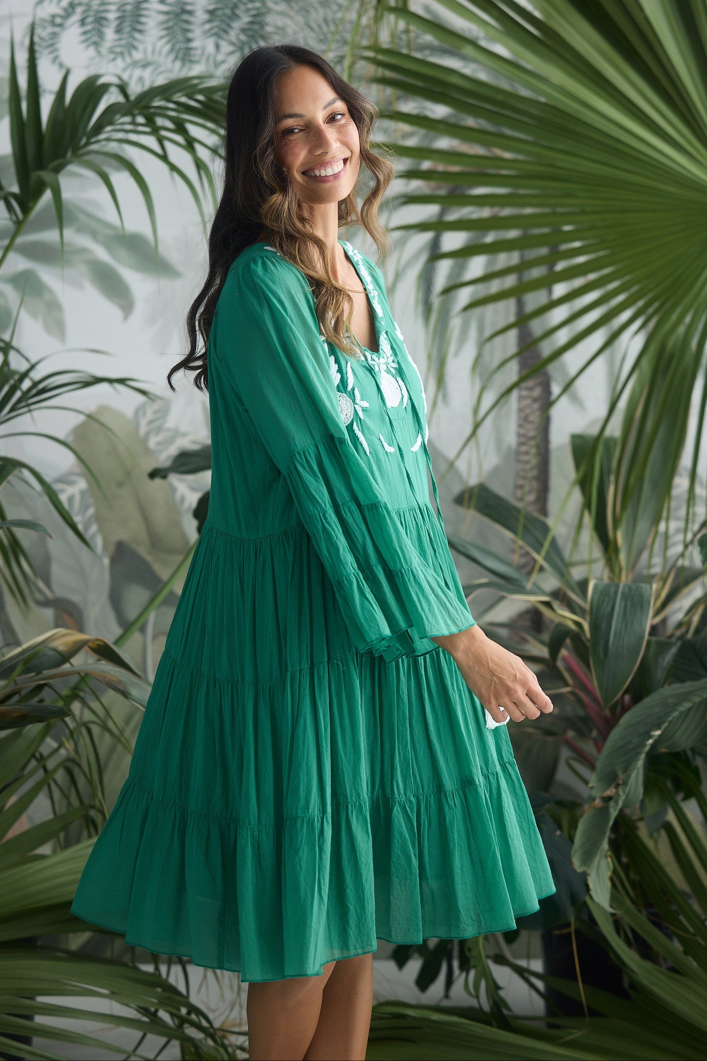 Woman in a green dress standing among tropical plants