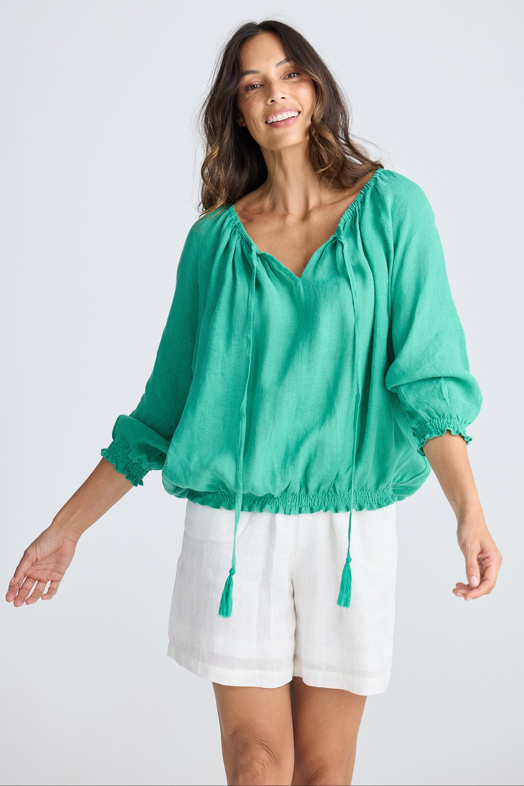 Woman wearing a green blouse and white shorts on a white background