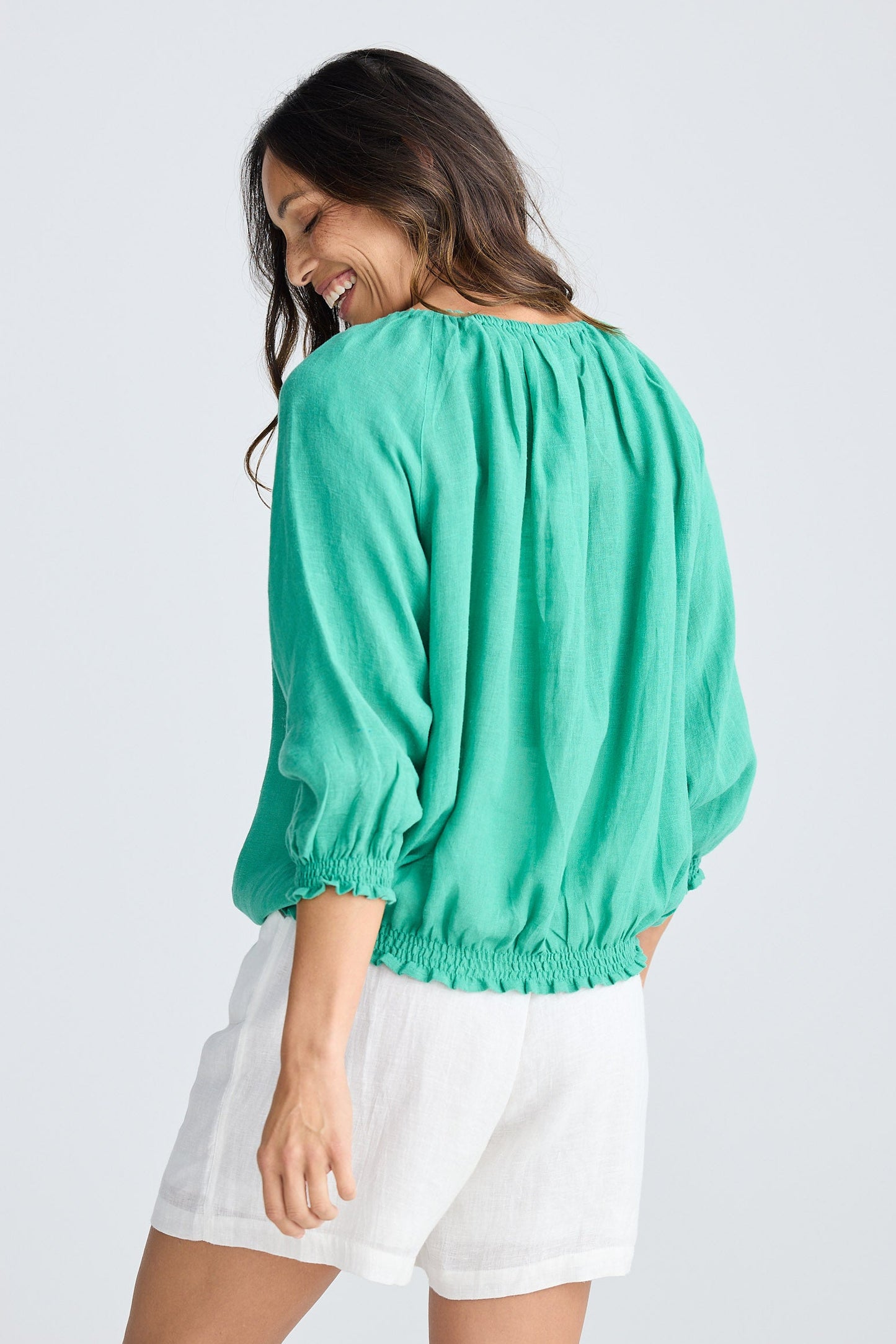 Woman wearing a green blouse and white shorts on a white background