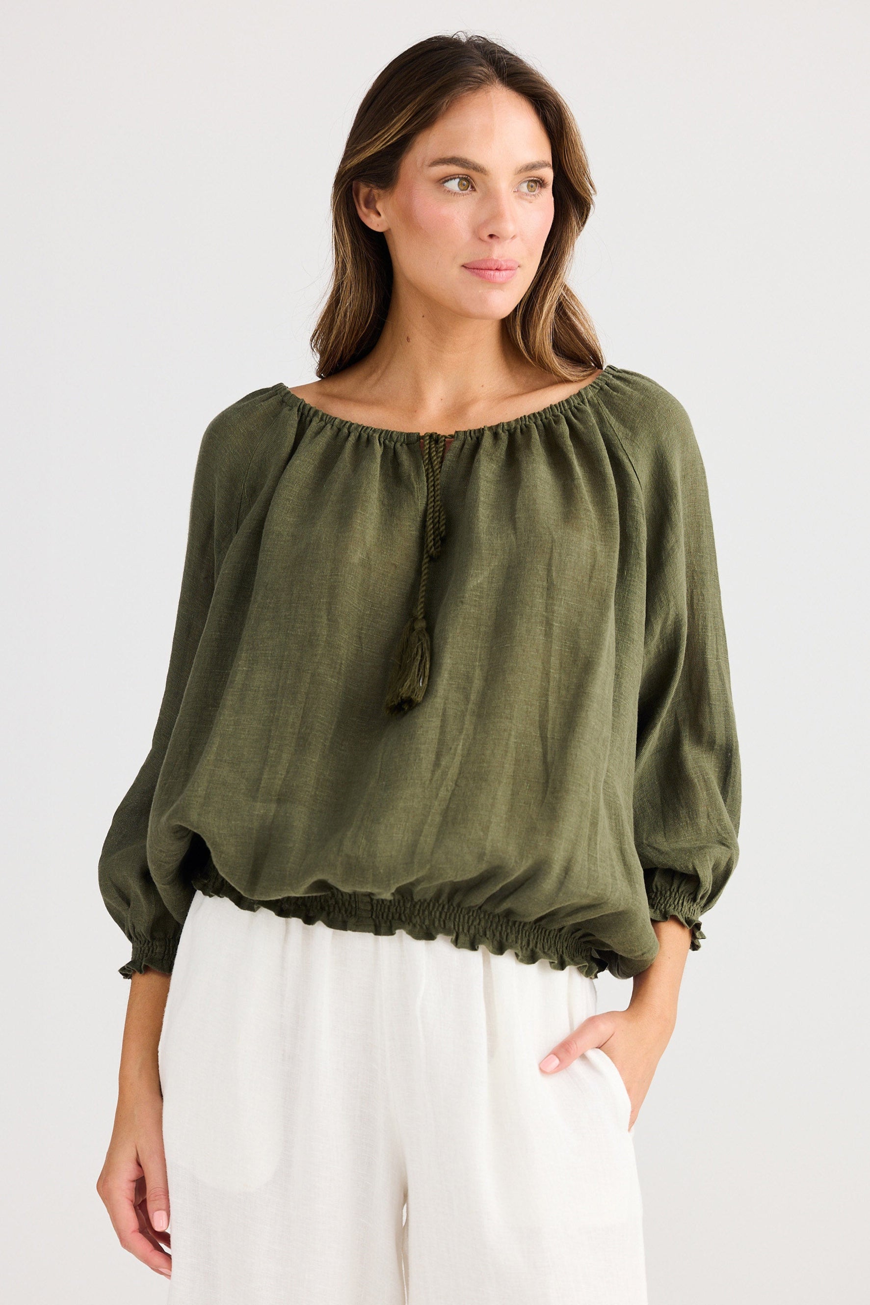 Woman wearing an olive green blouse with balloon sleeves on a white background