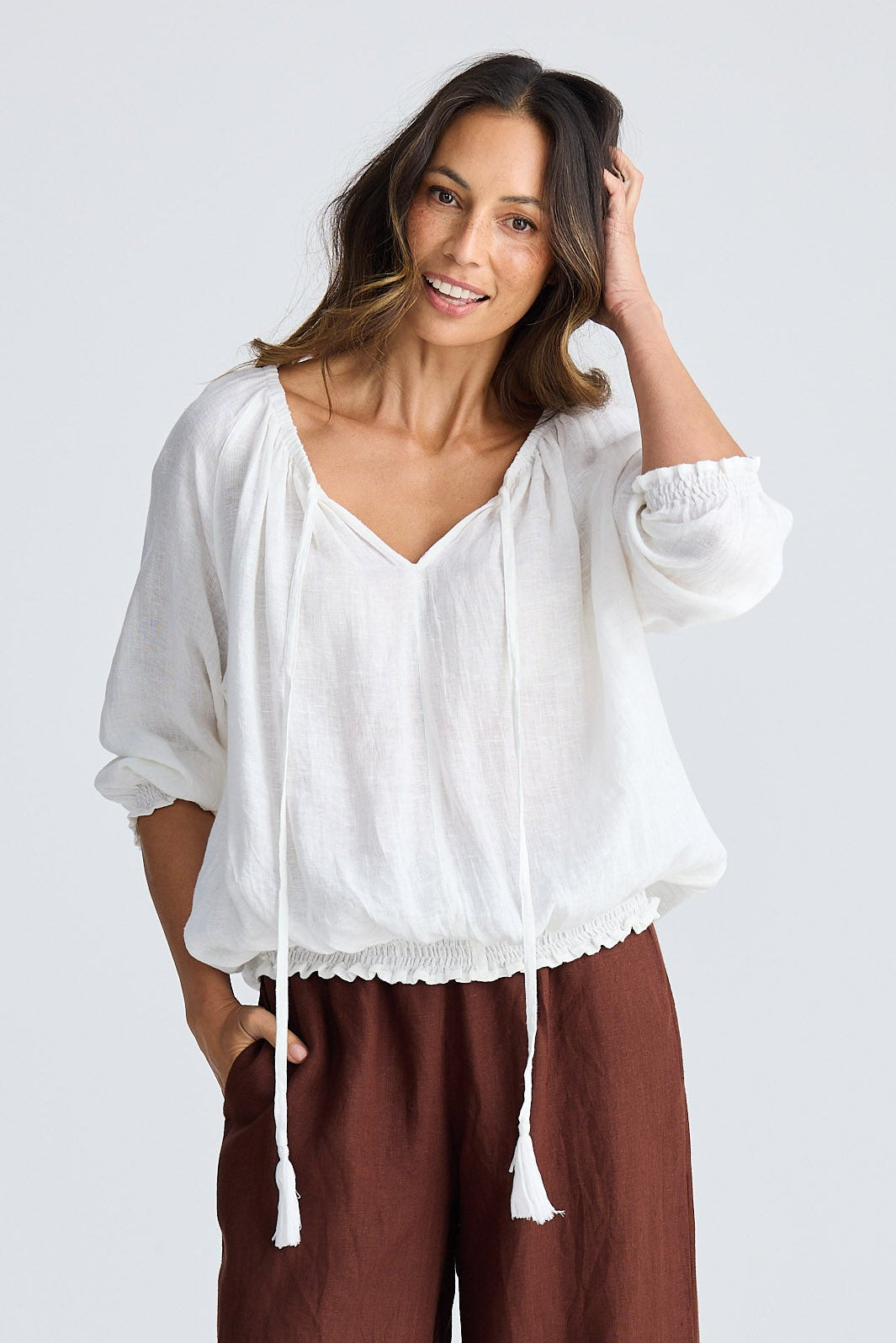 Woman wearing a white top and brown pants on a white background