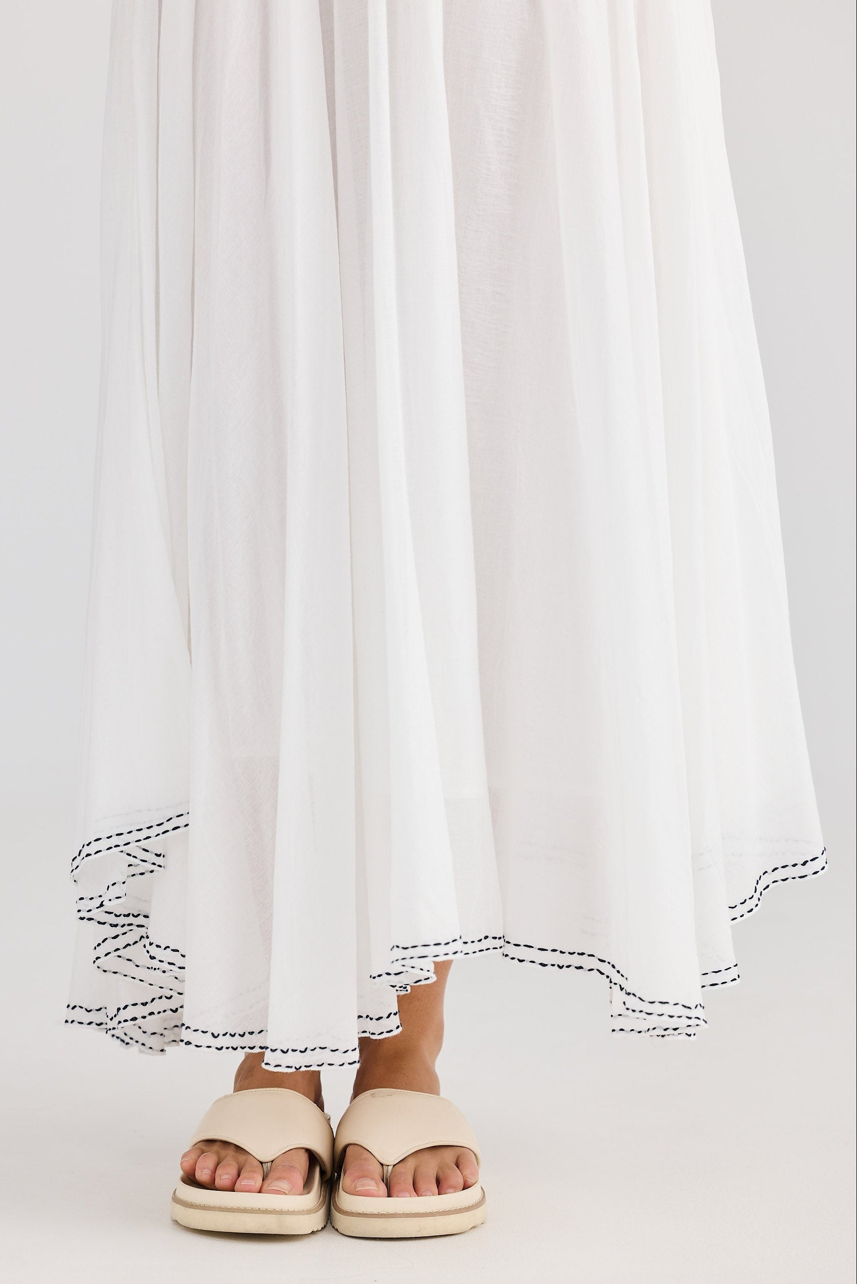 White skirt with lace trim worn by a person on a plain background
