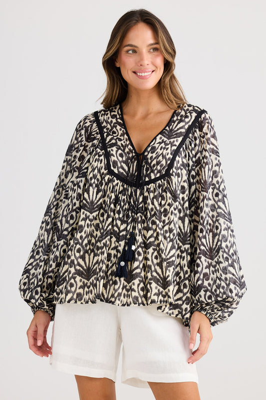 Woman wearing a leopard print blouse with tassels on a white background
