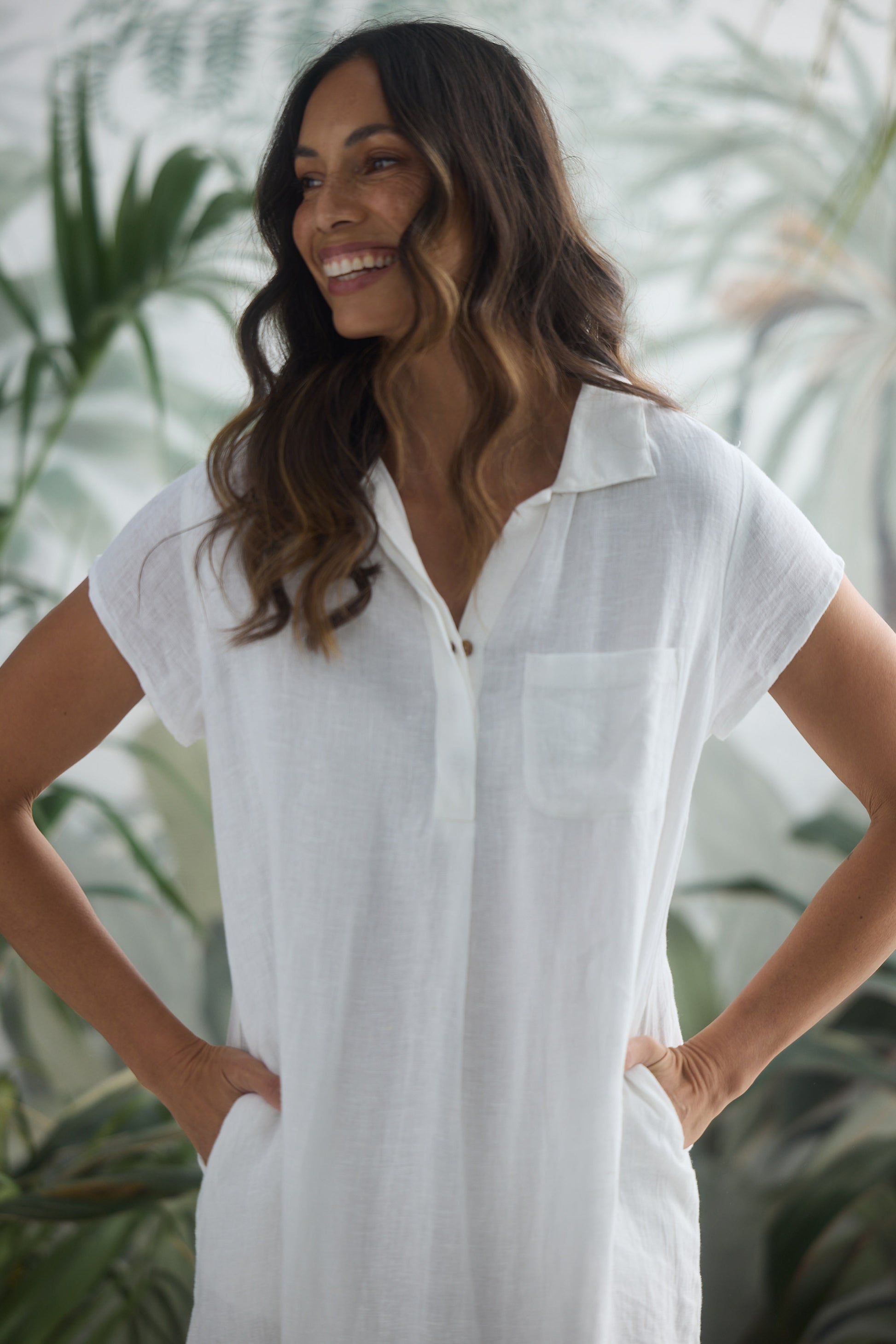Woman wearing a white dress with plants in the background