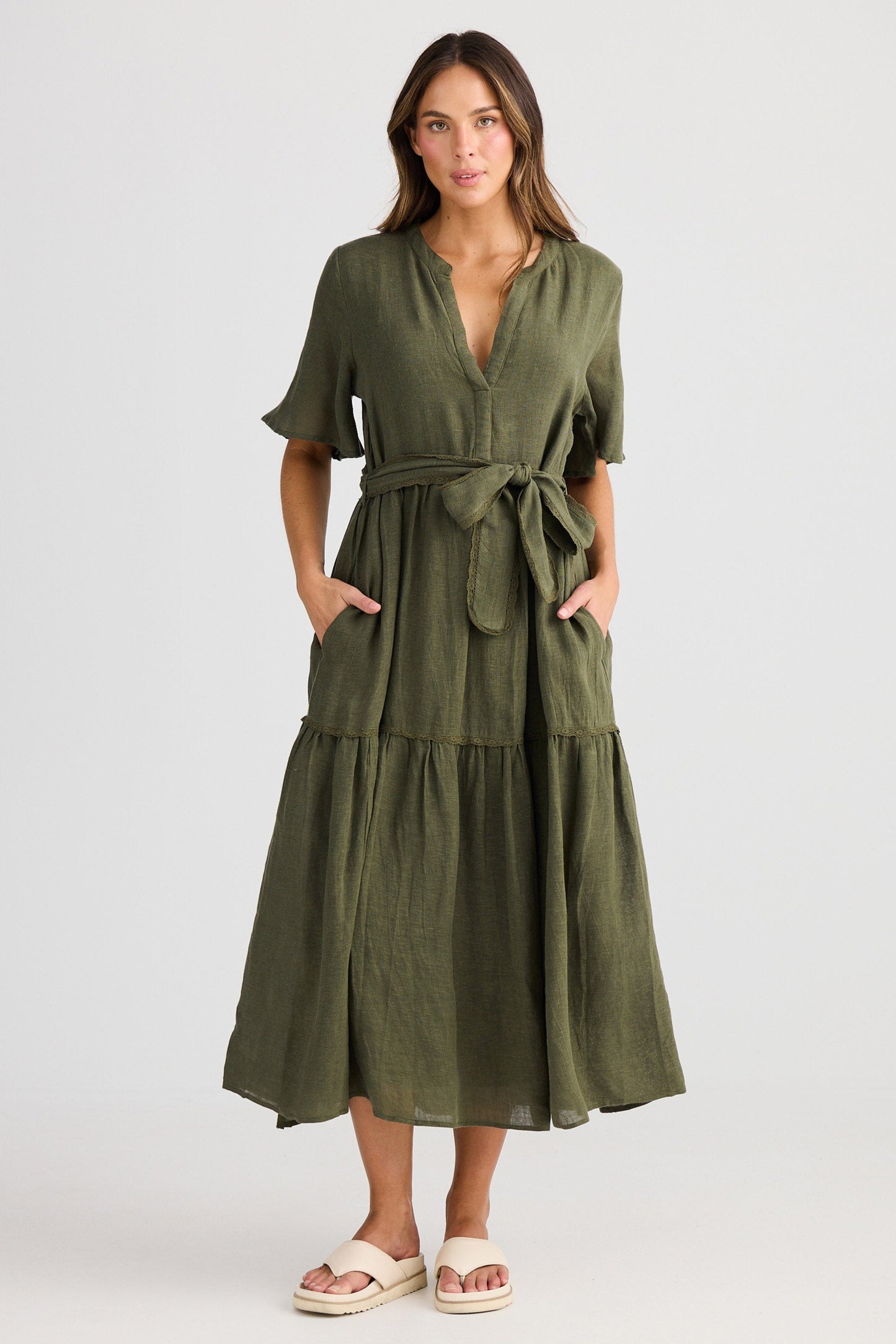 Woman wearing a green dress with a belt on a white background