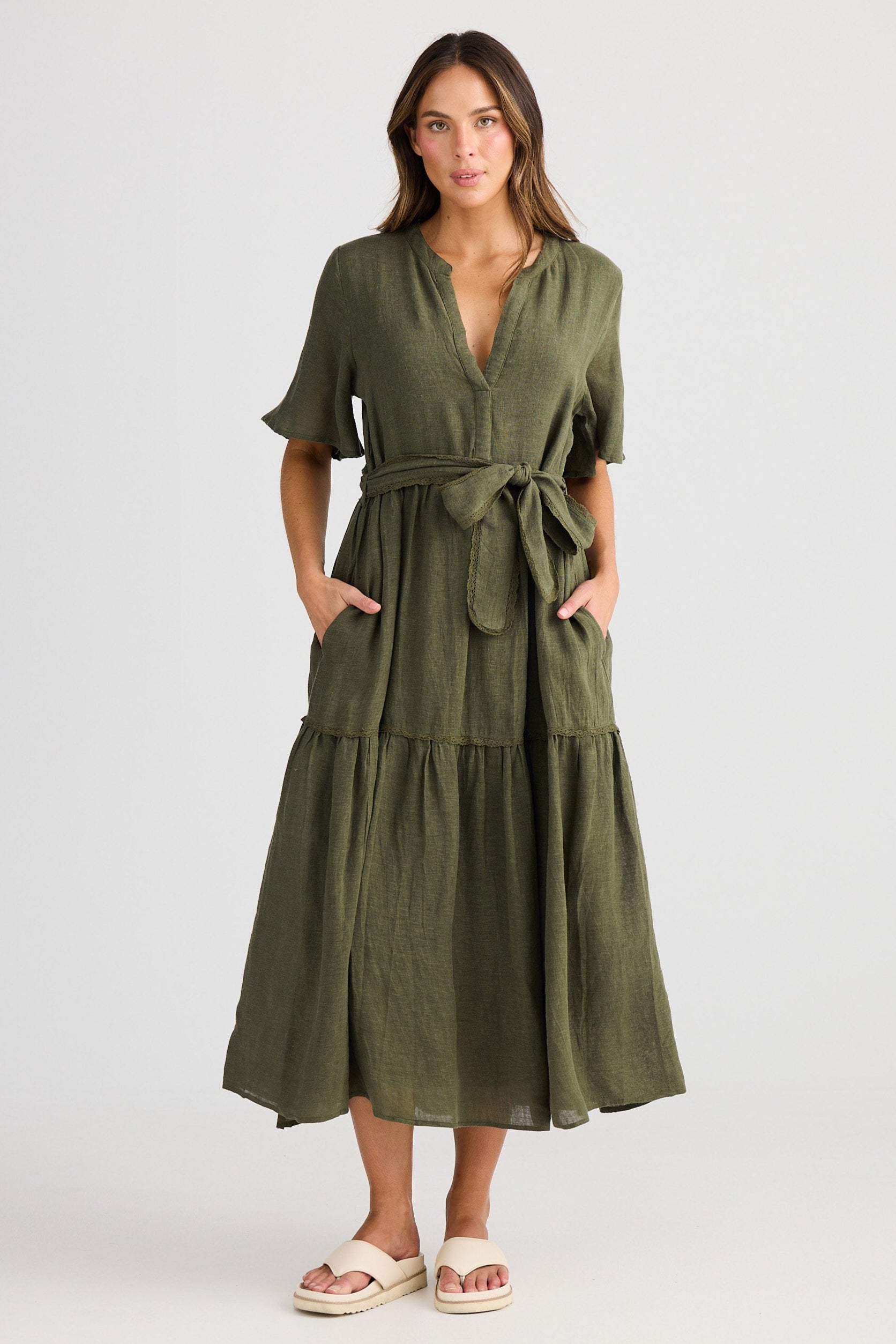 Woman wearing a green dress with a belt on a white background
