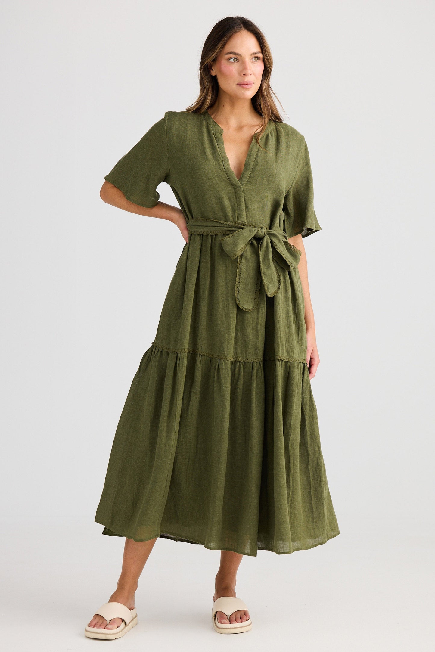 Woman wearing a green dress with a belt on a white background