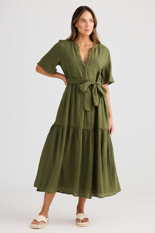 Woman wearing a green dress with a belt on a white background
