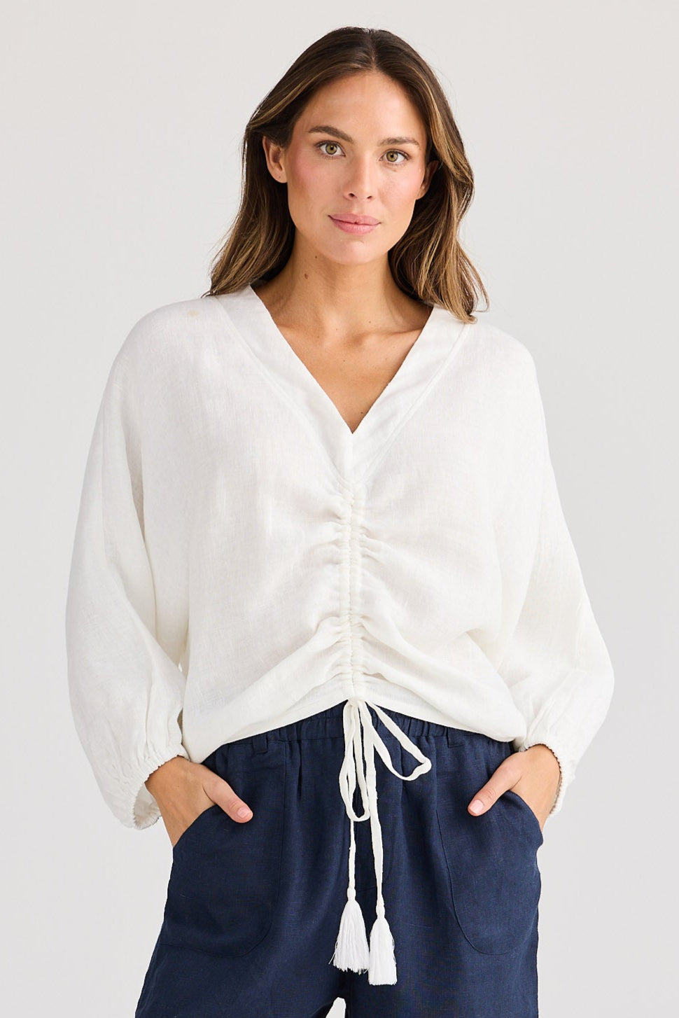 Woman wearing a white shirt and navy shorts on a plain background