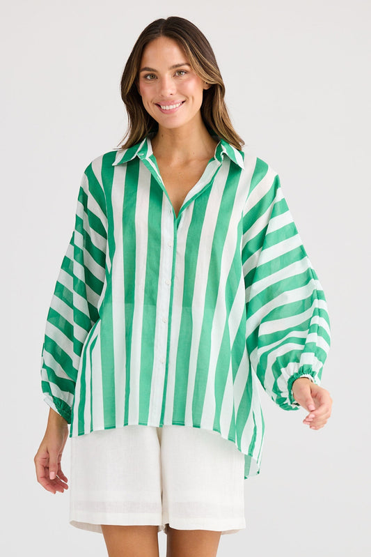 Woman wearing a green and white striped shirt and white shorts on a light gray background