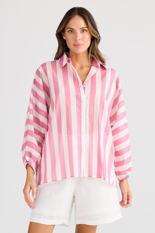 Woman wearing a pink and white striped shirt with white shorts on a white background