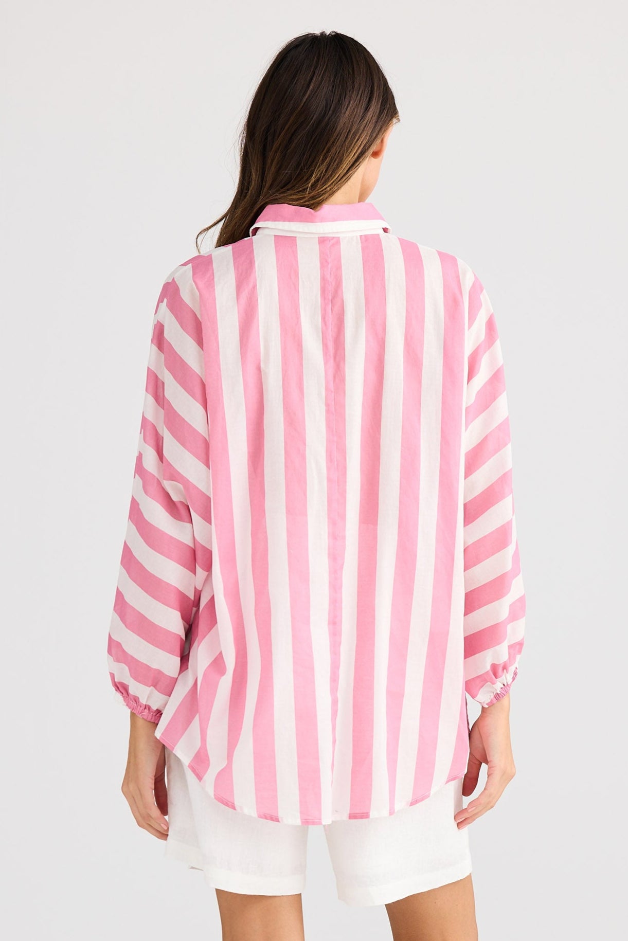 Woman wearing a pink and white striped shirt on a plain background
